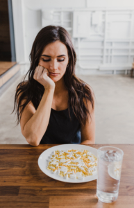 woman look disgusted at dietary supplement in pill form