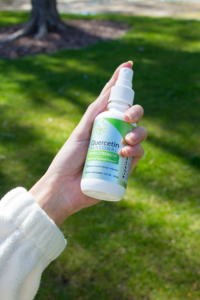 Woman holds Quercetin Seasonal immune support spray supplement