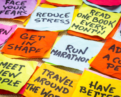 realistic and unrealistic new year goals or resolutions - colorful sticky notes on canvas