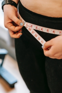 woman in black leggings measuring waist after detox weight loss
