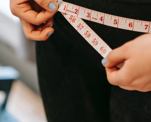 woman in black leggings measuring waist after detox weight loss