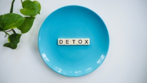 Blue plate with word Detox spelled in wooden letters promoting detox weight loss