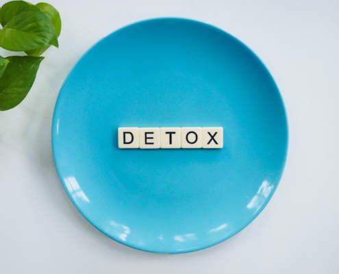 Blue plate with word Detox spelled in wooden letters promoting detox weight loss