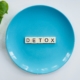 Blue plate with word Detox spelled in wooden letters promoting detox weight loss